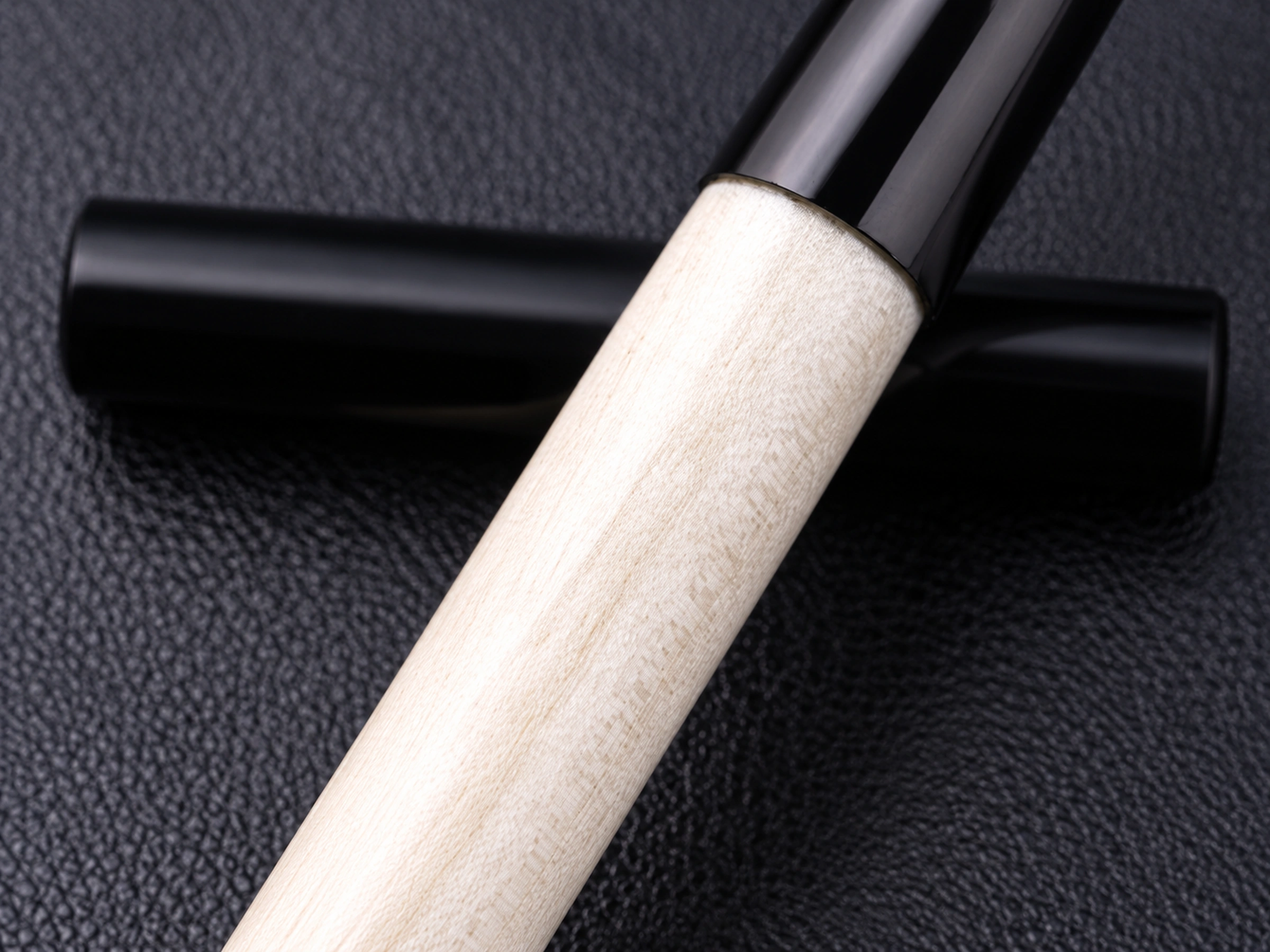 Ivory lacquered grip joined to a glossy black ferrule, with its separate protective cap behind