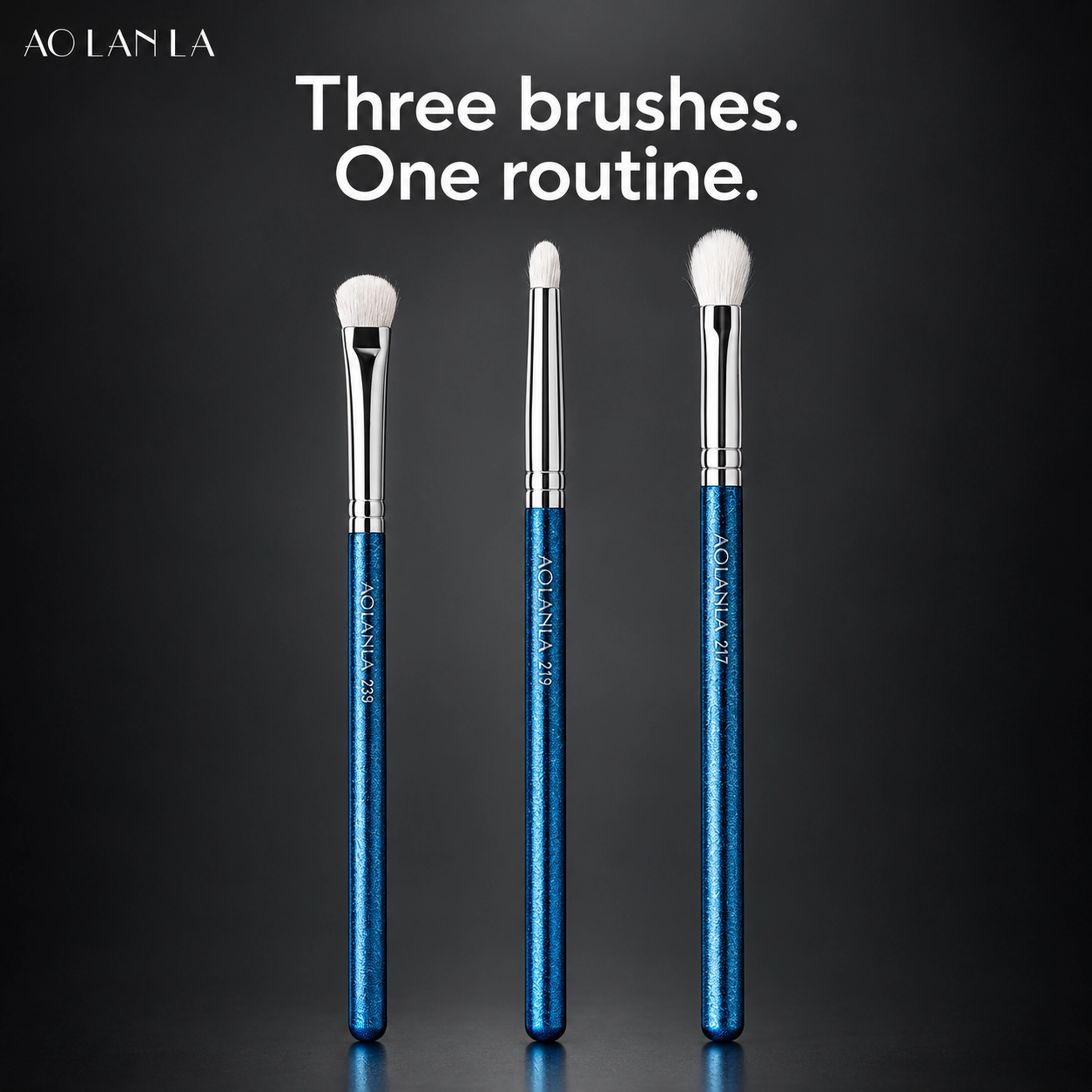 Three complete white-wool eye brushes against charcoal