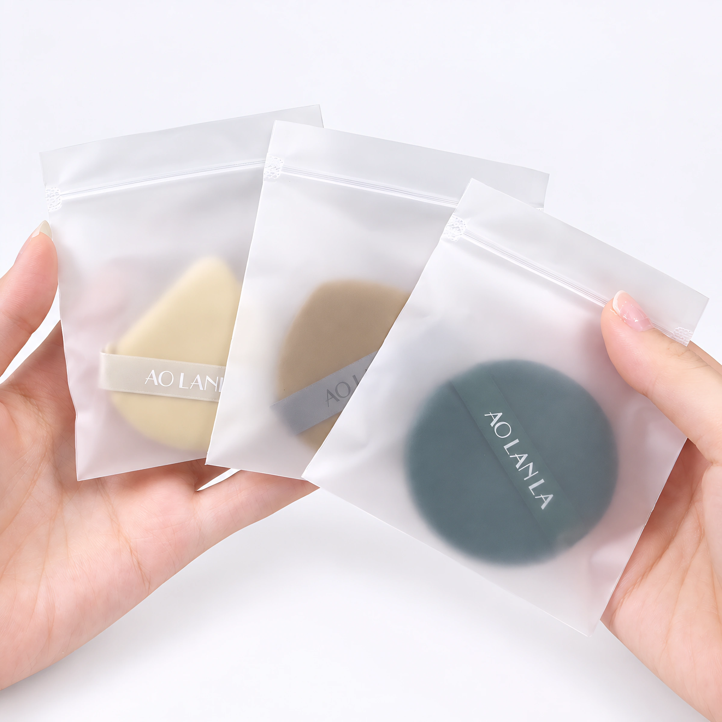 Three puffs inside separate frosted zip bags, held in the hands