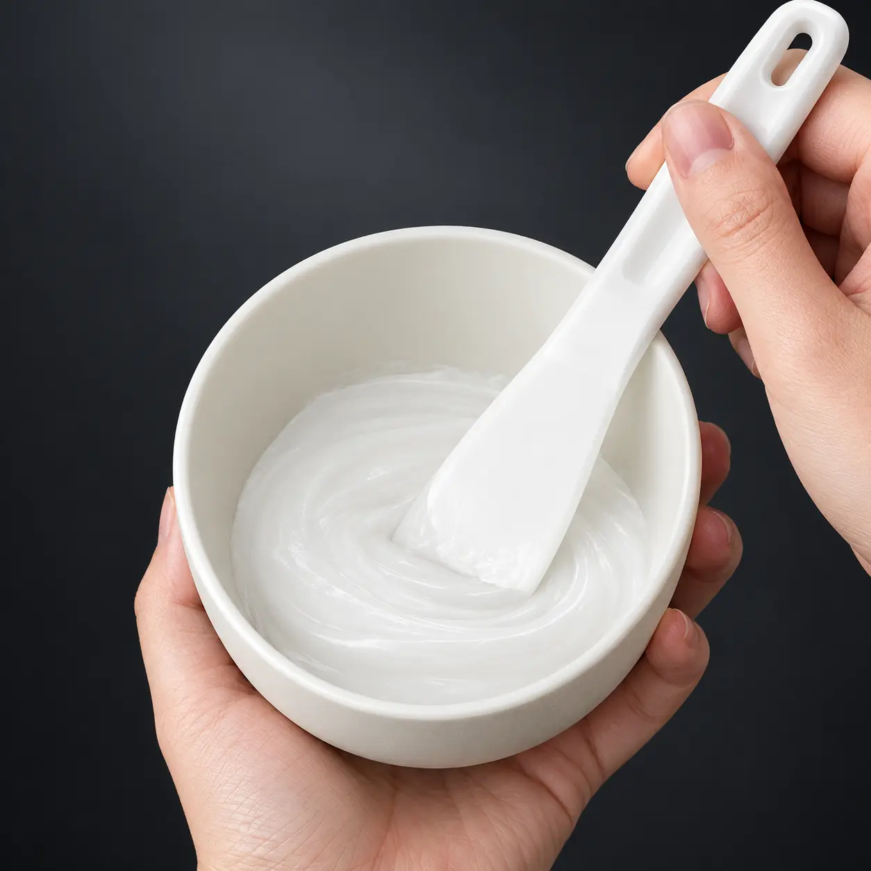 Silicone spatula mixing a mask in the off-white bowl