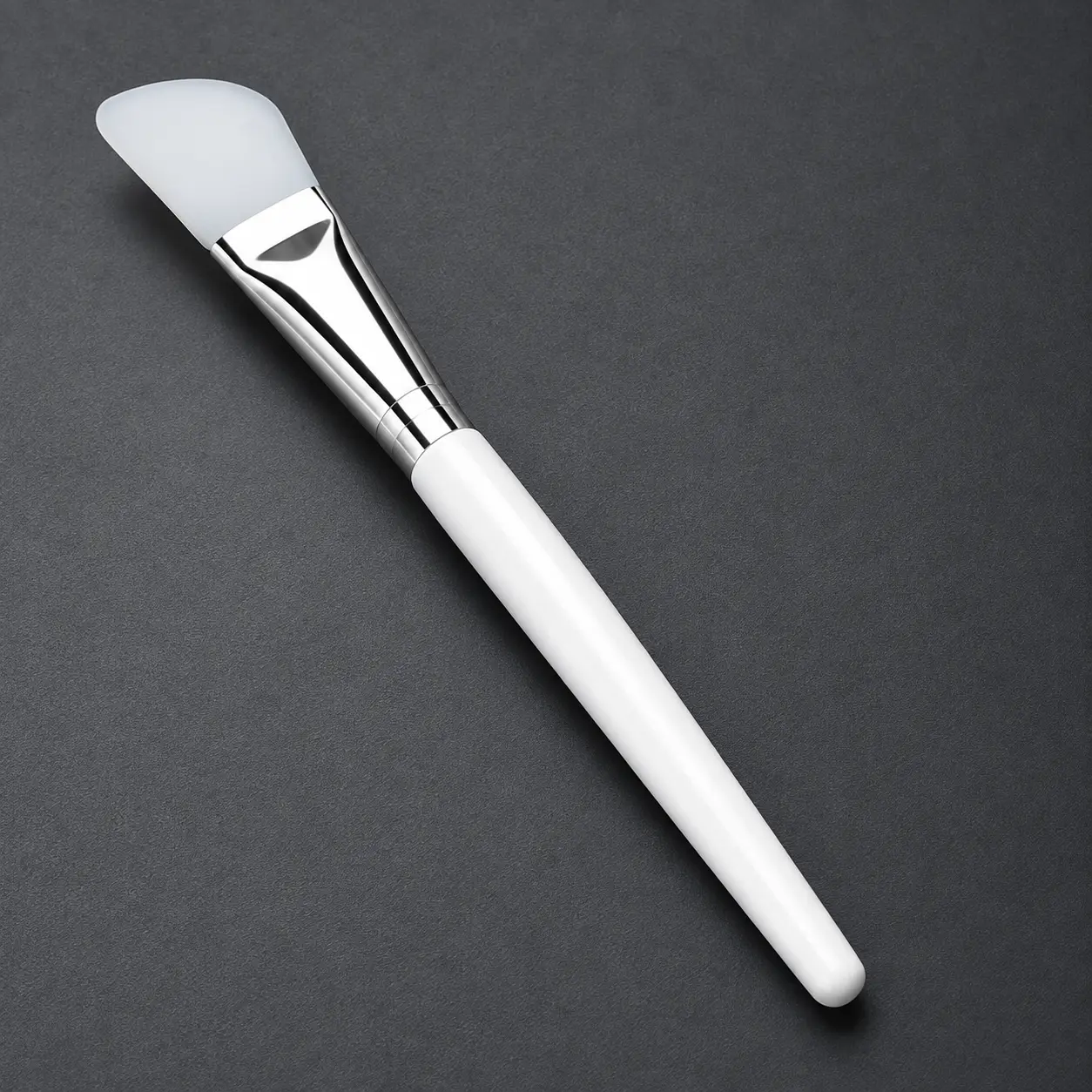 Curved white silicone mask brush with a silver ferrule