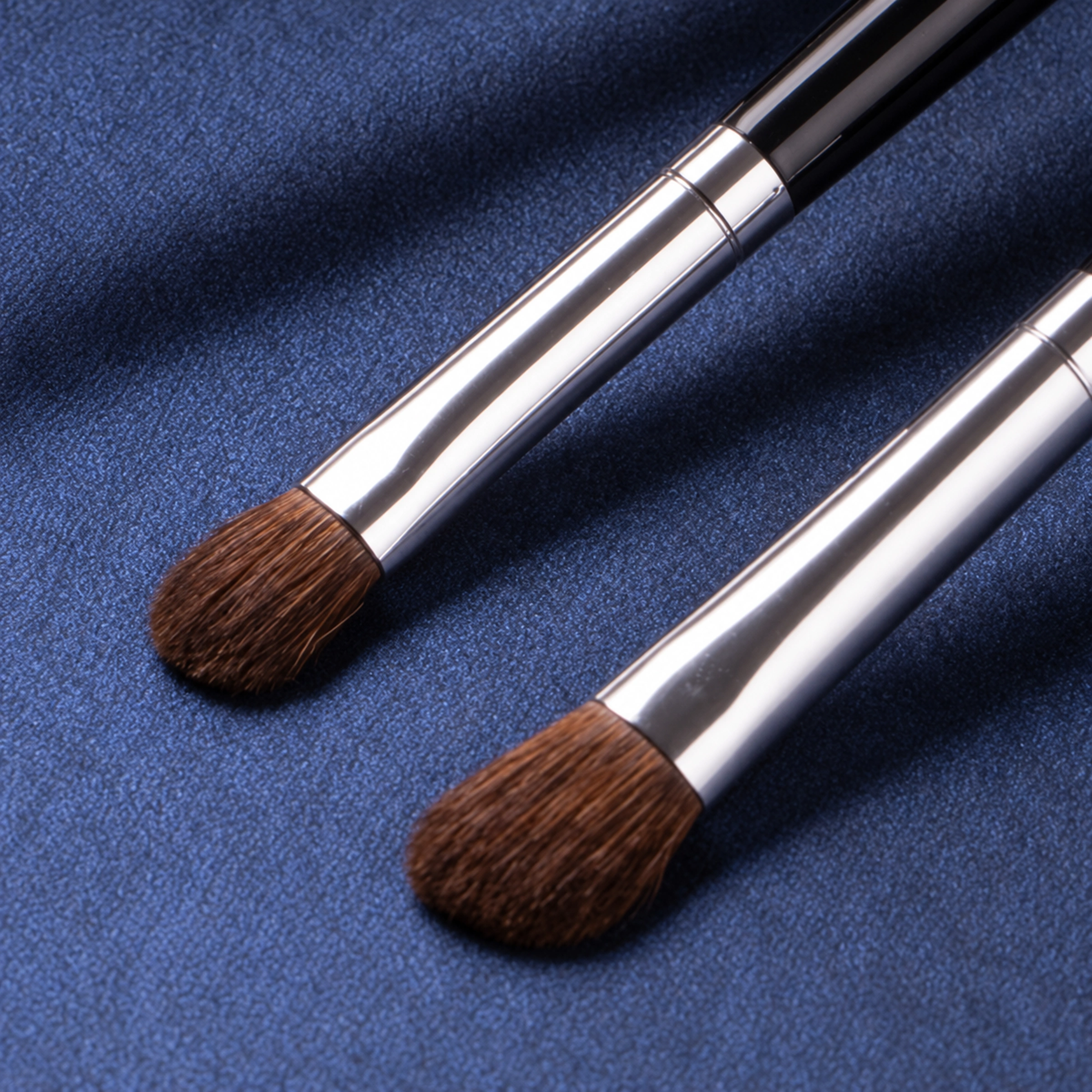 Two rounded brown powder brush heads and polished silver-tone ferrules