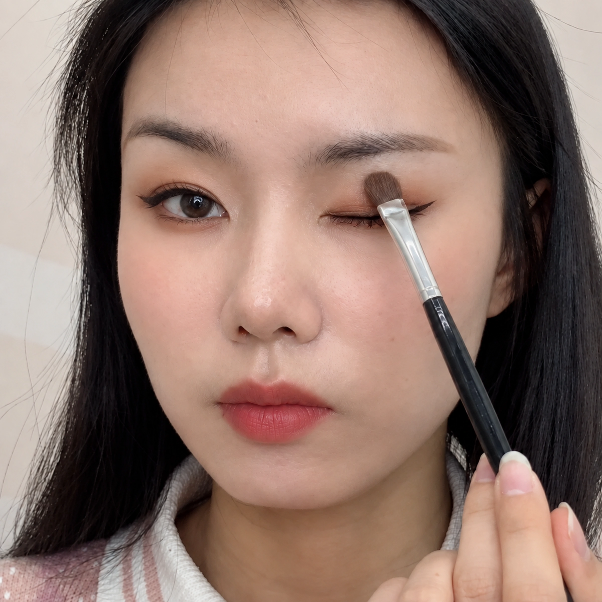 14 black-handled shader applying eyeshadow to a closed eyelid