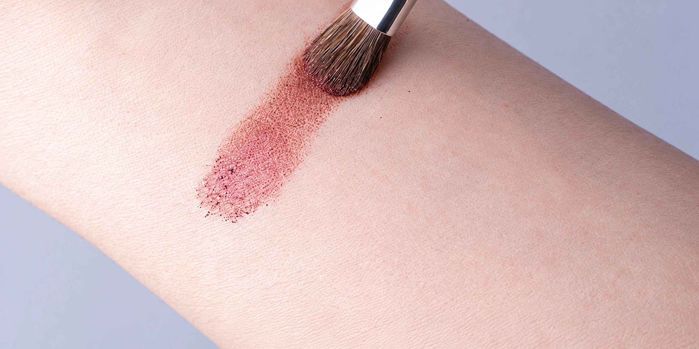 Original No.15 brush in light contact with a powder swatch on a wrist
