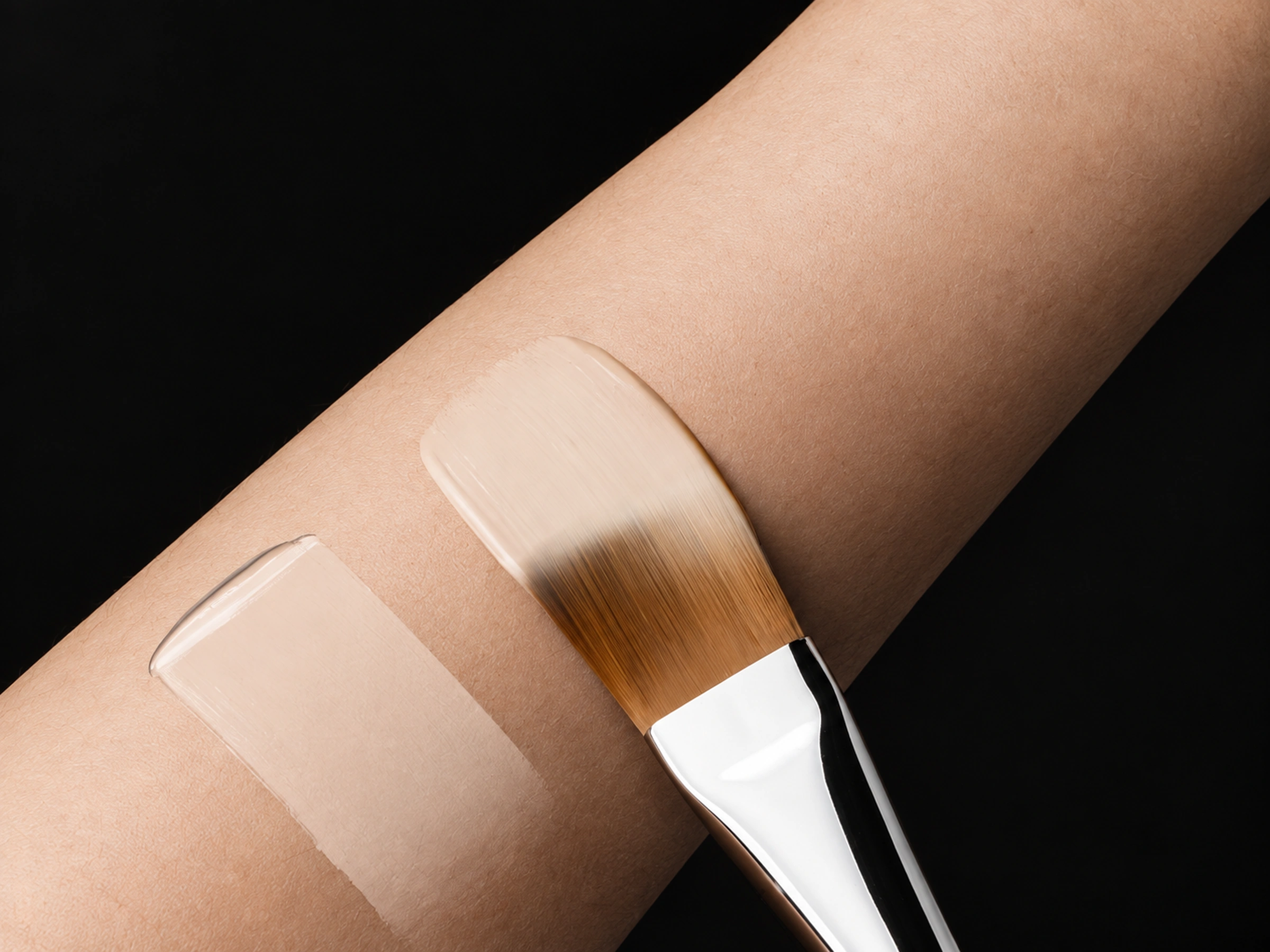 No191 brush laying a thin pale cream layer on a forearm, with its full working head visible
