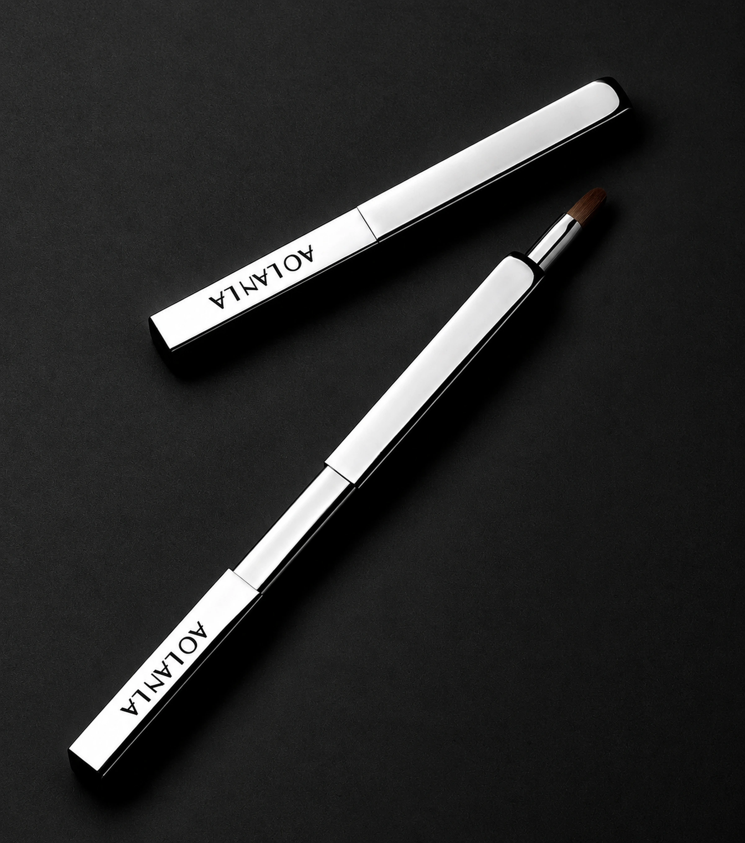 The same silver retractable lip brush shown closed and extended on a charcoal surface