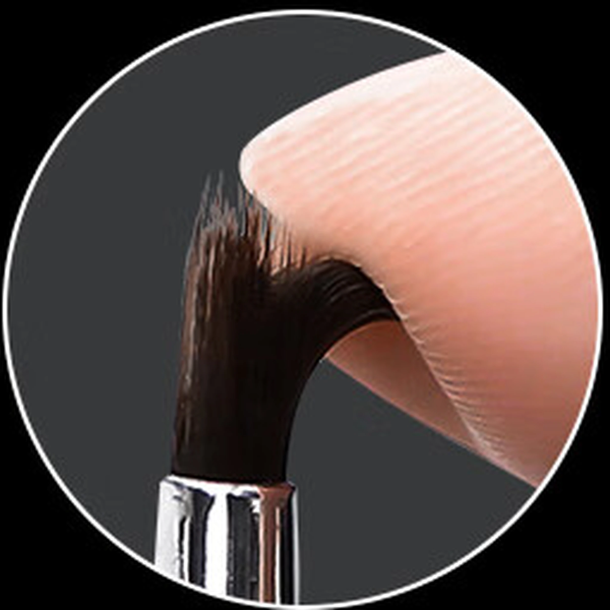 The original dark synthetic lip-brush fibres gently flexing against a fingertip
