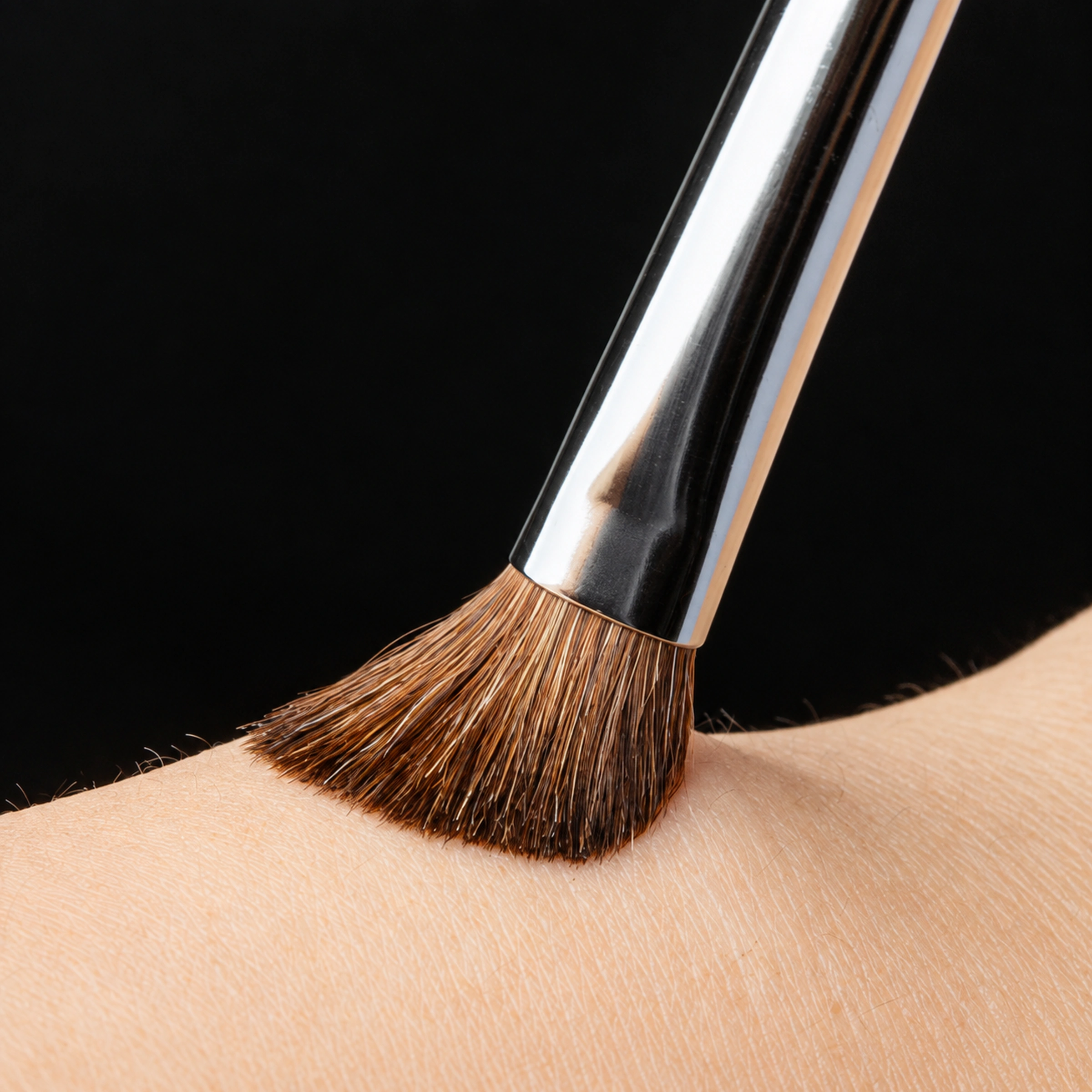 The angled pony-hair brush gently flexing against skin