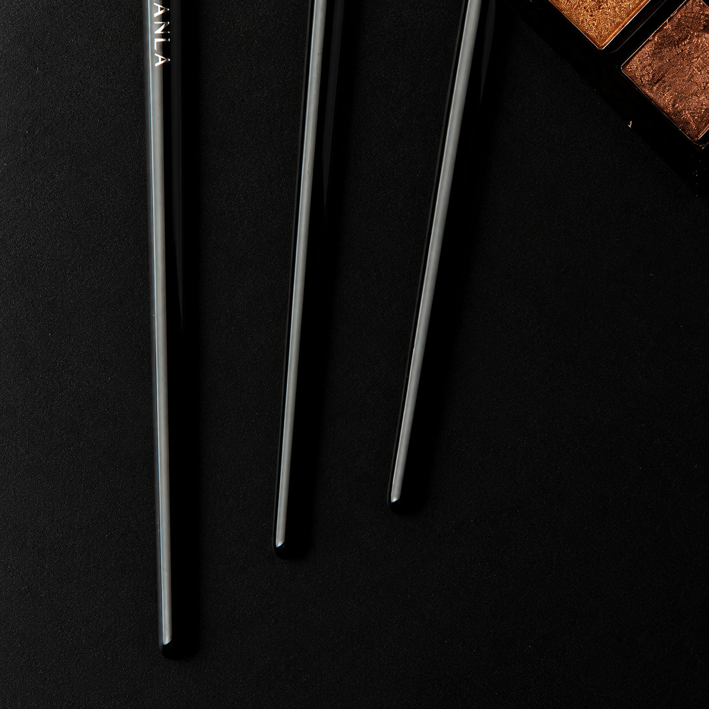 The three slender black handles and rounded handle ends of the Master eye brush set