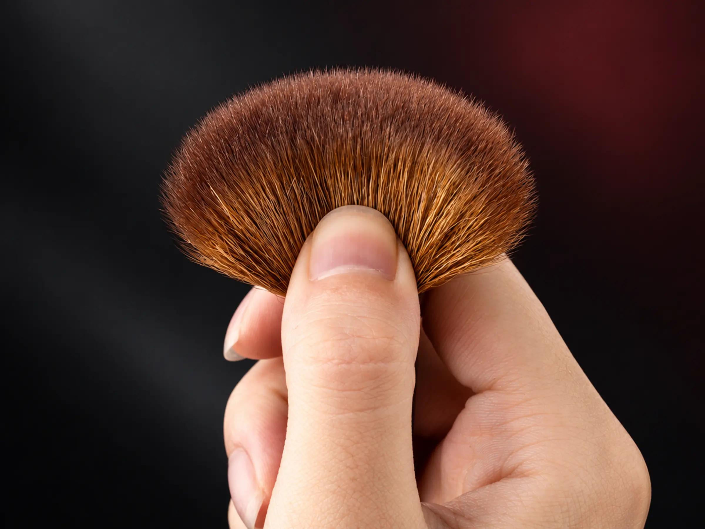 One hand gently compressing the Red Night natural-hair brush head to show flexible contact