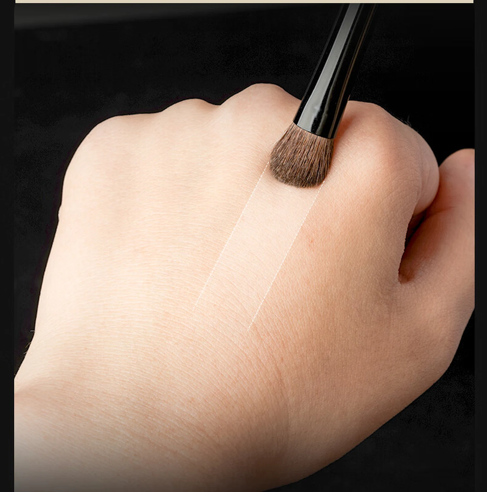 Brush sweeping colour across hand skin in a soft band